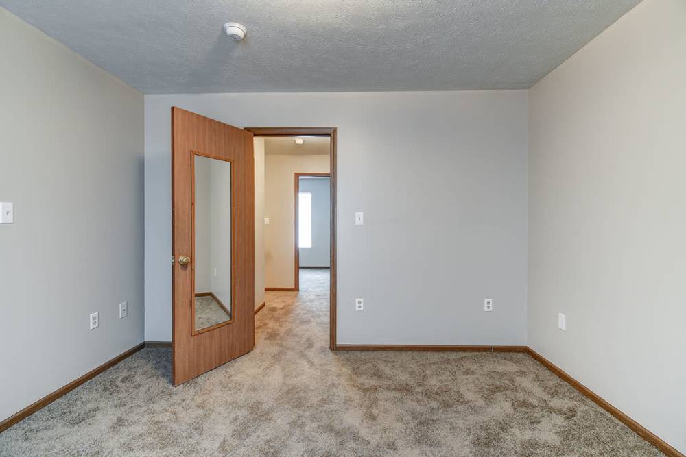 Spacious room with carpeted flooring and a door with a mirror at Cedar Glen I in Morgantown, West Virginia