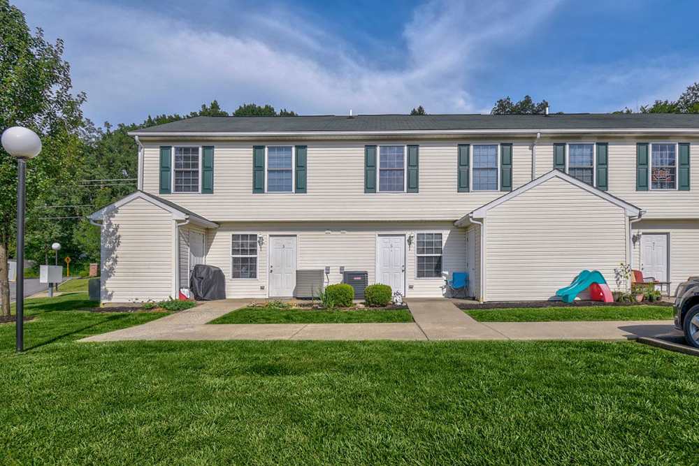 Two-story apartment community with green lawns, walkways, and outdoor seating areas at Canterbury Place in Elkins, West Virginia