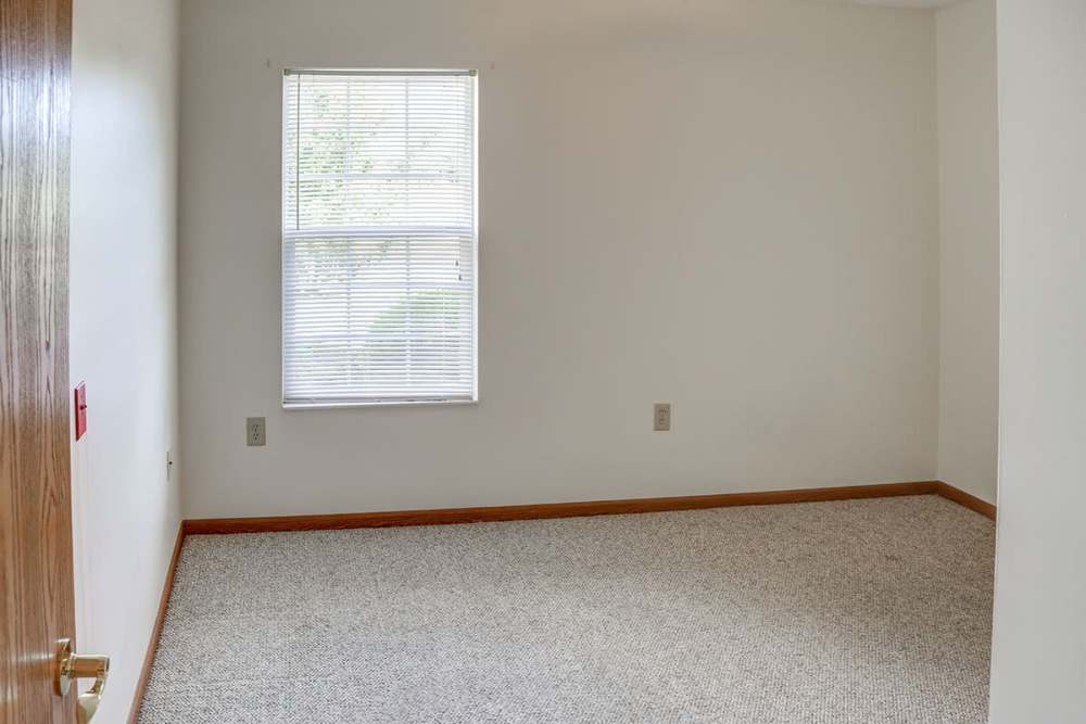 Empty room with beige carpet and window allowing natural light in at Heritage Greene in Washington Court House, Ohio