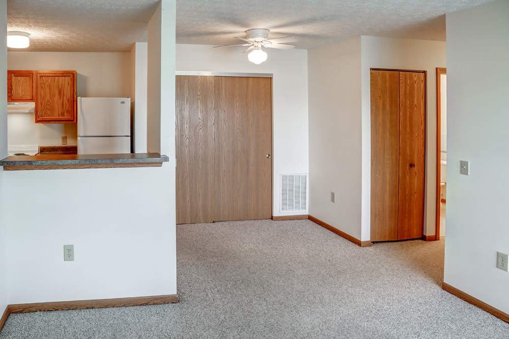 Open layout apartment with carpet flooring, kitchen featuring wood cabinets and white appliances at Heritage Greene in Washington Court House, Ohio