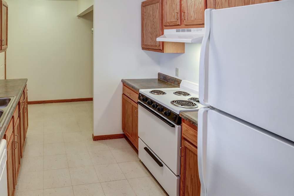 Kitchen featuring wood cabinetry, white appliances, and ample counter space in an open layout at Heritage Greene in Washington Court House, Ohio