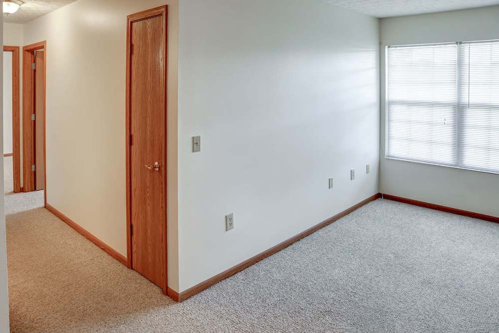 Bright, spacious hallway with carpet flooring and doors to multiple rooms, natural light from window at Heritage Greene in Washington Court House, Ohio