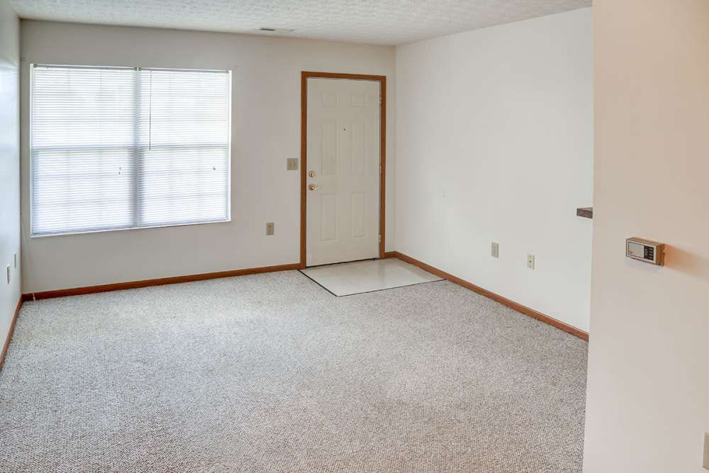 Spacious living room with carpeted flooring and natural light from large window at Heritage Greene in Washington Court House, Ohio