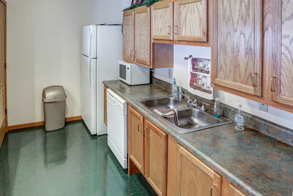 Kitchen with wood cabinets, stainless steel appliances, and a double sink with countertop space at Heritage Greene in Washington Court House, Ohio