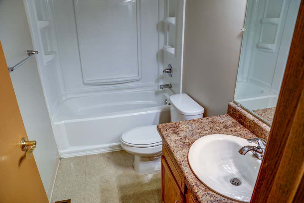 Bathroom featuring a granite countertop, bathtub, and modern fixtures with a clean design at Mason Greene in Monticello, Kentucky