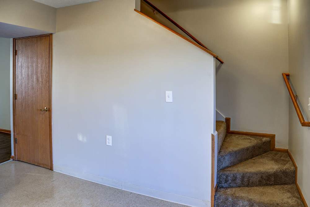 Staircase leading to upper level with carpeted steps and wooden railing at Mason Greene in Monticello, Kentucky