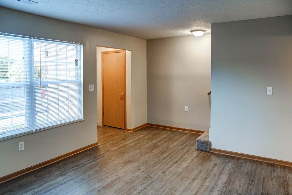 Bright living area with wood-style flooring and large windows, inviting natural light at Mason Greene in Monticello, Kentucky