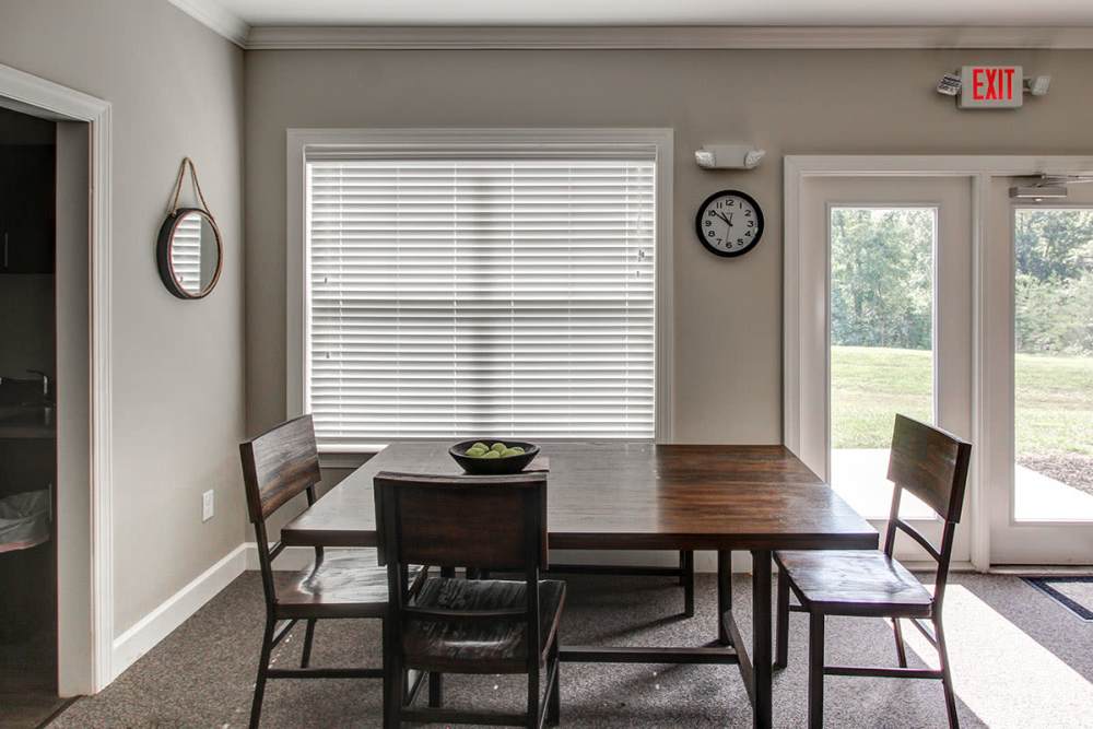 Bright dining area with a wooden table, four chairs, and natural light from large windows at Northside Drive Apartments in Crossville, Tennessee