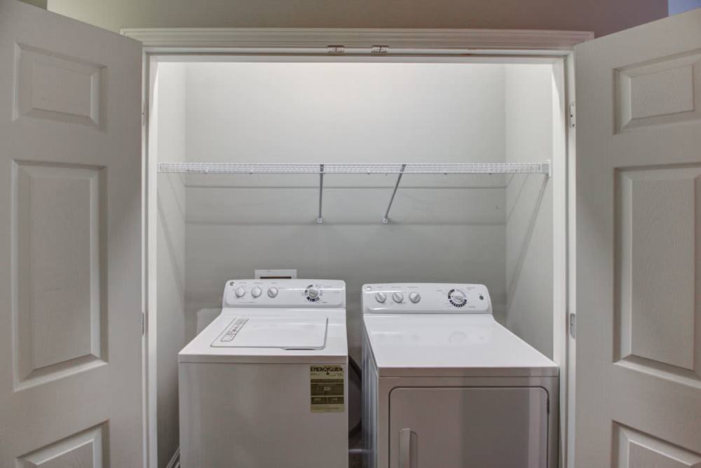 Laundry closet featuring stacked washer and dryer with shelving above at Northside Drive Apartments in Crossville, Tennessee