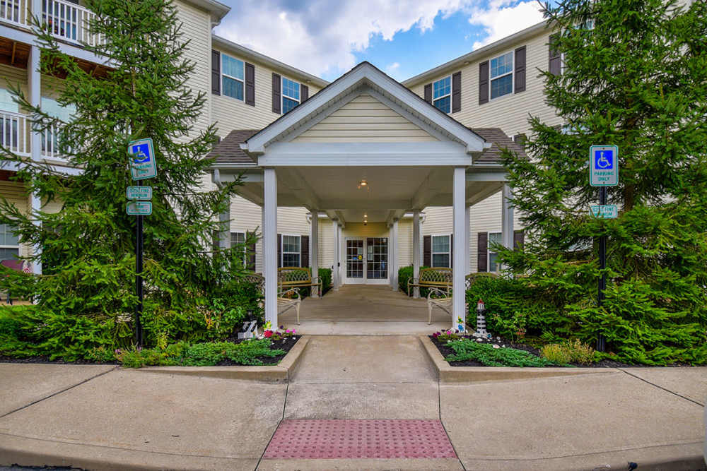 Welcoming entrance with landscaped greenery and accessible parking spots at Norwood Greene Senior Living in Marietta, Ohio