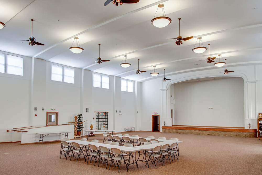 Spacious community room with seating area, ceiling fans, and natural light from large windows at Sycamore House Senior Living in Durand, Michigan