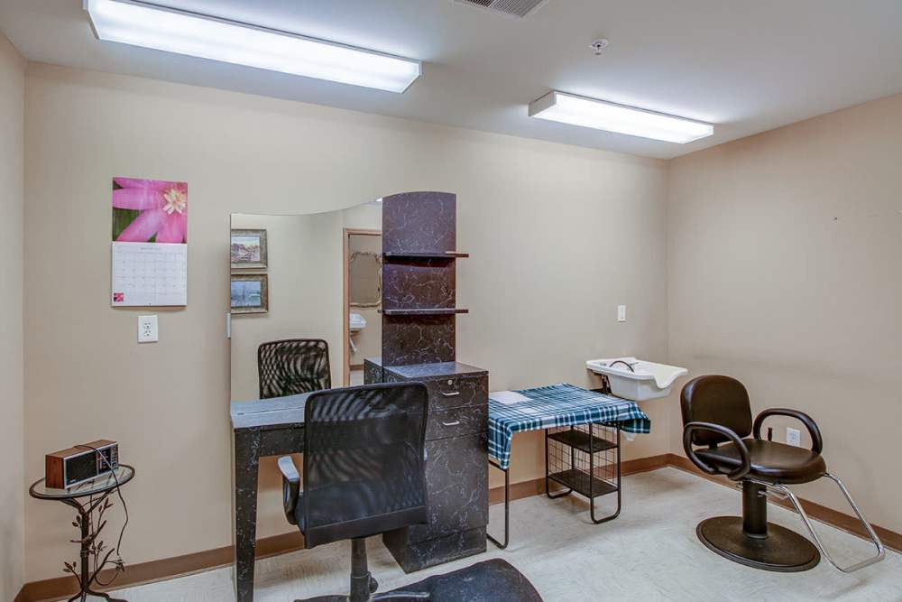 Salon space with styling chairs, mirrors, and a countertop with a sink and checkered cloth at Sycamore House Senior Living in Durand, Michigan