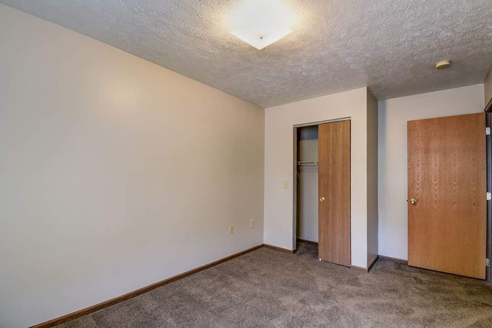 Empty room with carpeted flooring, two wooden doors, and a ceiling light fixture at Stone Brooke in Weirton, West Virginia