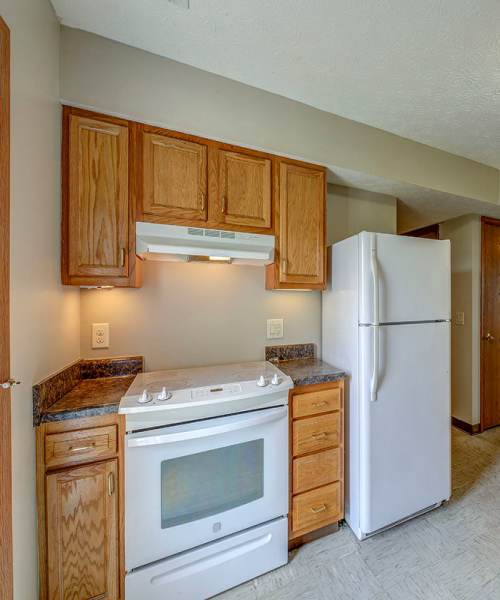 White refrigerator next to wooden cabinets at Orchard Glen in Orrville, Ohio
