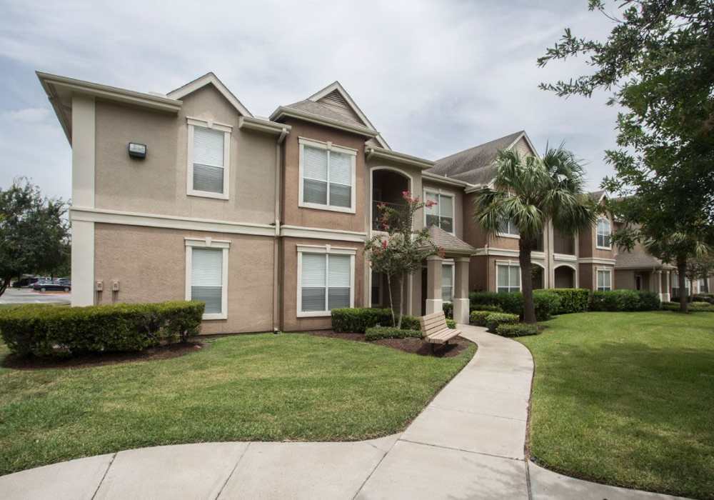 Two-story apartment building with manicured lawns and pathway at Las Palmas Apartments in Brownsville, Texas