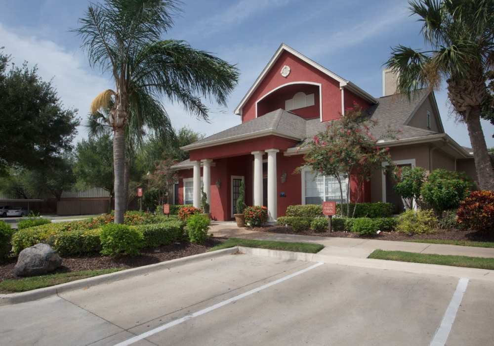 Welcoming apartment community entrance with lush landscaping and palm trees at Rincon Apartments in McAllen, Texas