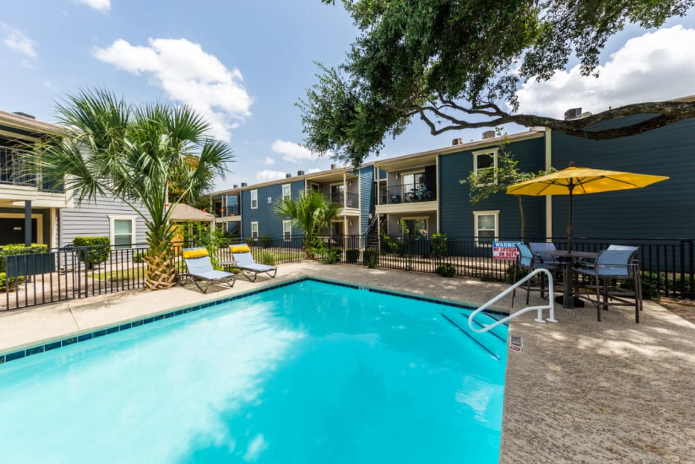 End of lounge pool with umbrella covered table and chairs in background at Austin Midtown in Austin, Texas