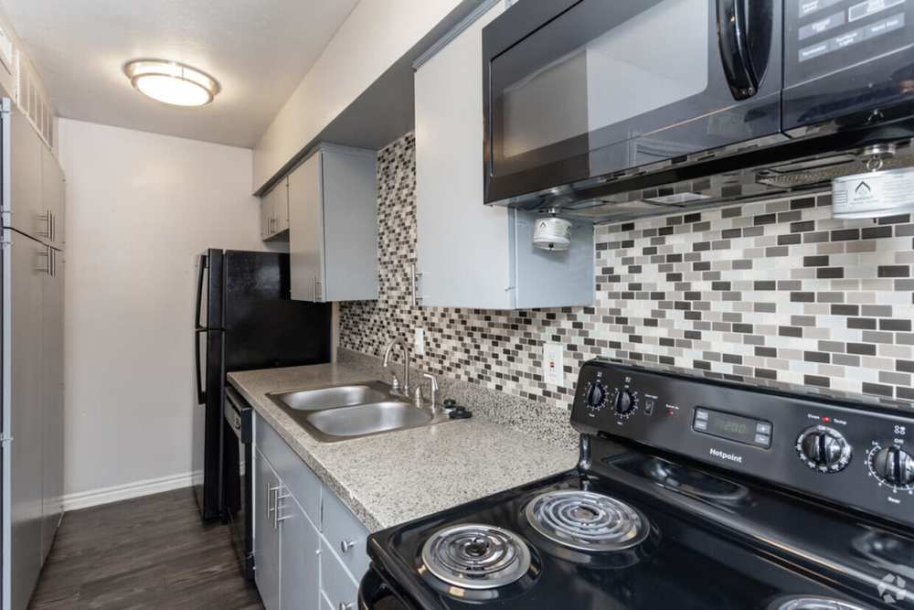 Modern kitchen with balck appliances at Tribecca Pointe Apartments in Hurst, Texas