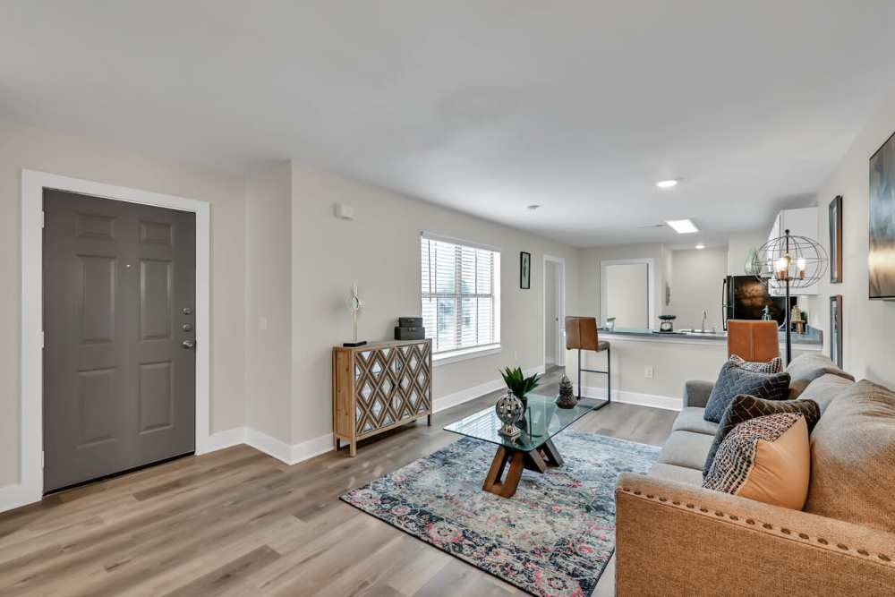 Spacious living room with couch, glass coffee table and hard wood-style flooring at Woodforest Chase in Houston, Texas