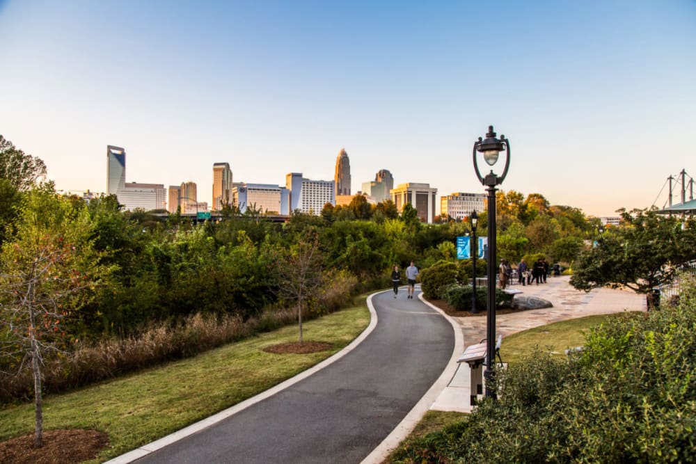 Couple running on paved path through park area at sunset near Marq Midtown 205 in Charlotte, North Carolina