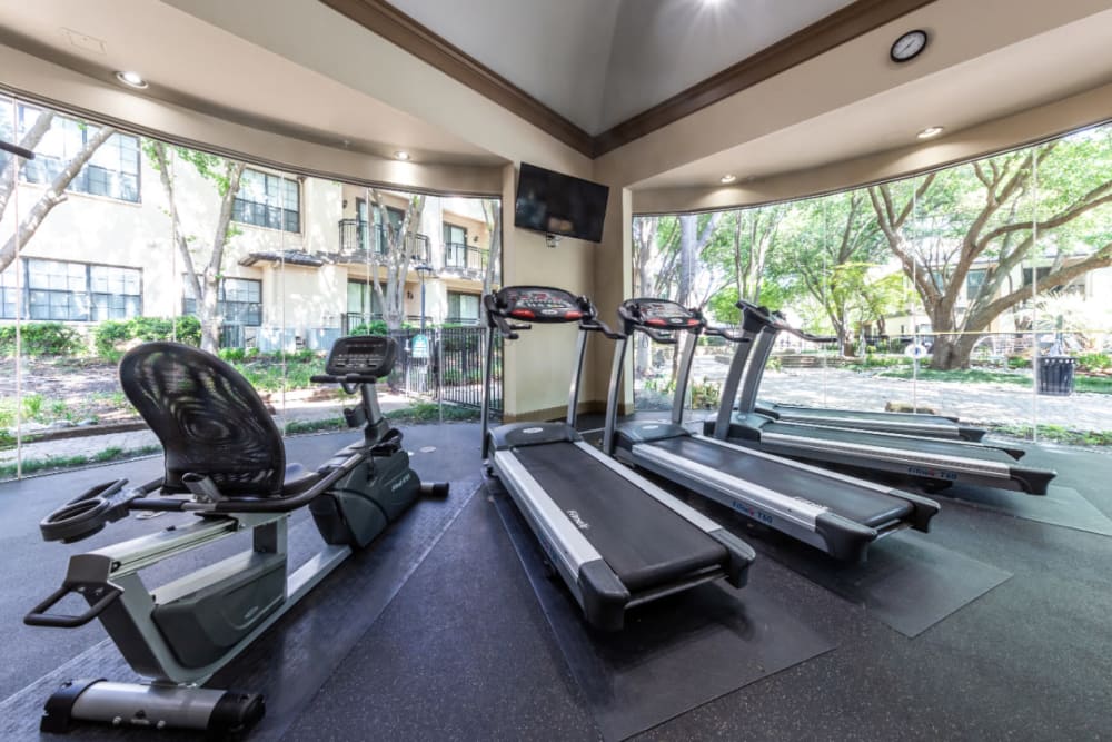 Sitting exercise bike and treadmills with view of the pool deck at Marquis at Waterview in Richardson, Texas