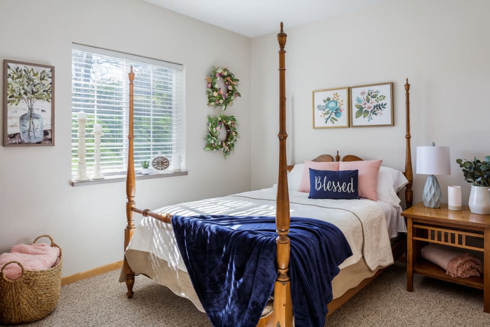 Resident bedroom with a side table and wall art at Glenwood Place in Marshalltown, Iowa.