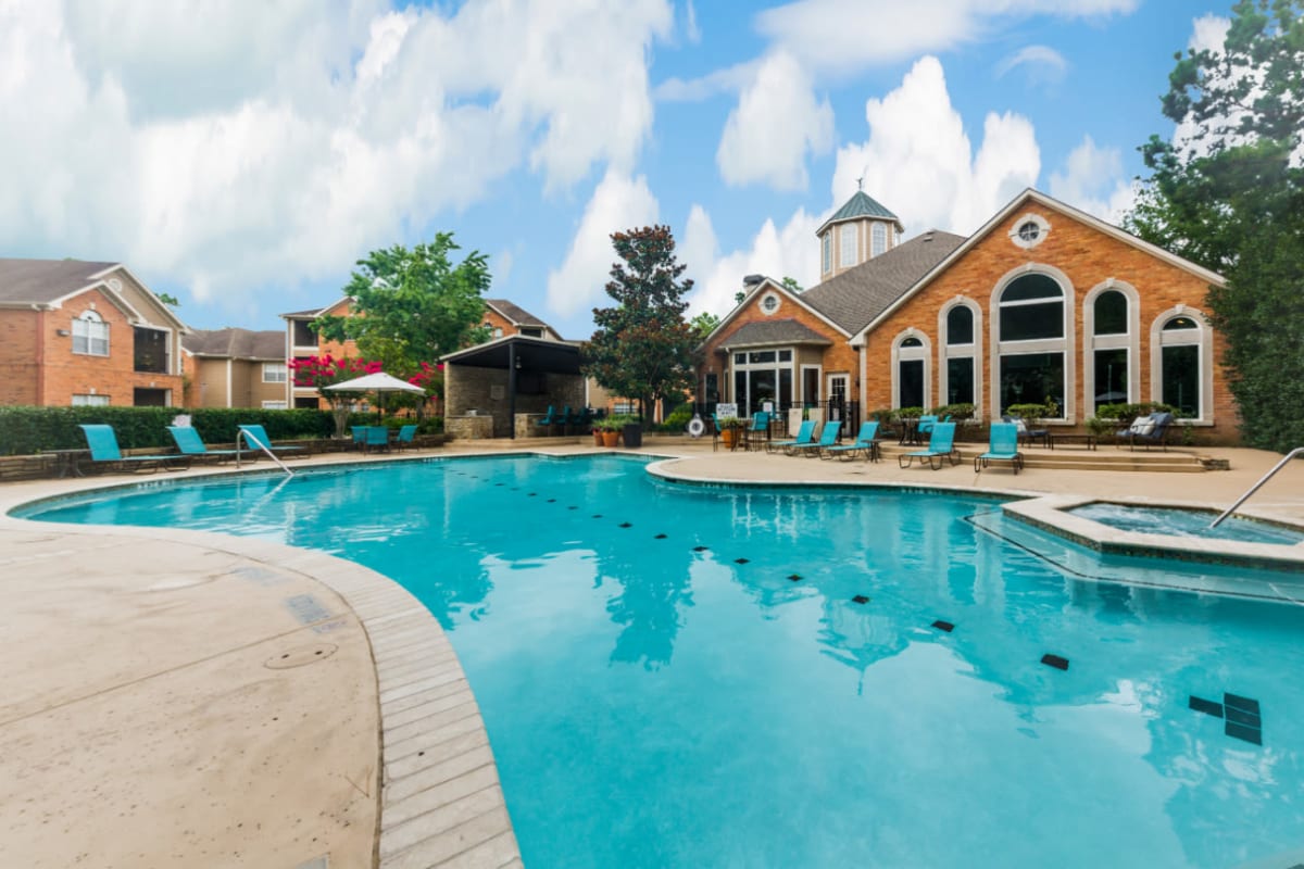 Sparkling pool with hot tub and turquoise lounge chairs at Marquis at Kingwood in Kingwood, Texas