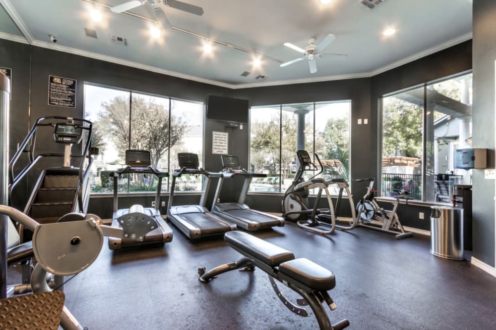 Cardio machines with large windows towards pool at Marquis at Stonegate in Fort Worth, Texas