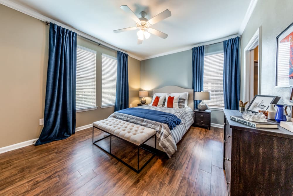 Spacious bedroom with multiple windows, ceiling fan, and wood flooring at Marquis at Stone Oak in San Antonio, Texas