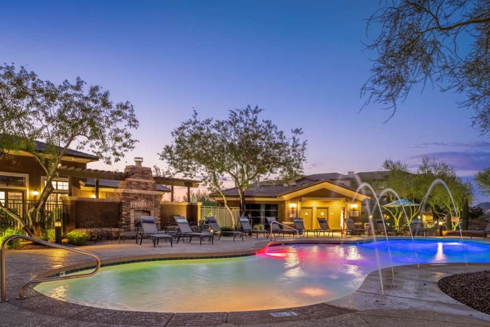 Colorfully lighted pool with water features at sunset at Marquis at Sonoran Preserve in Phoenix, Arizona