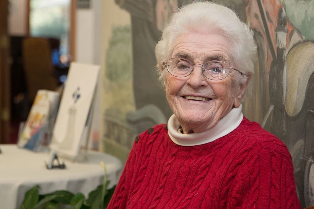 Resident in a red sweater smiling at White Oaks in Lawton, Michigan