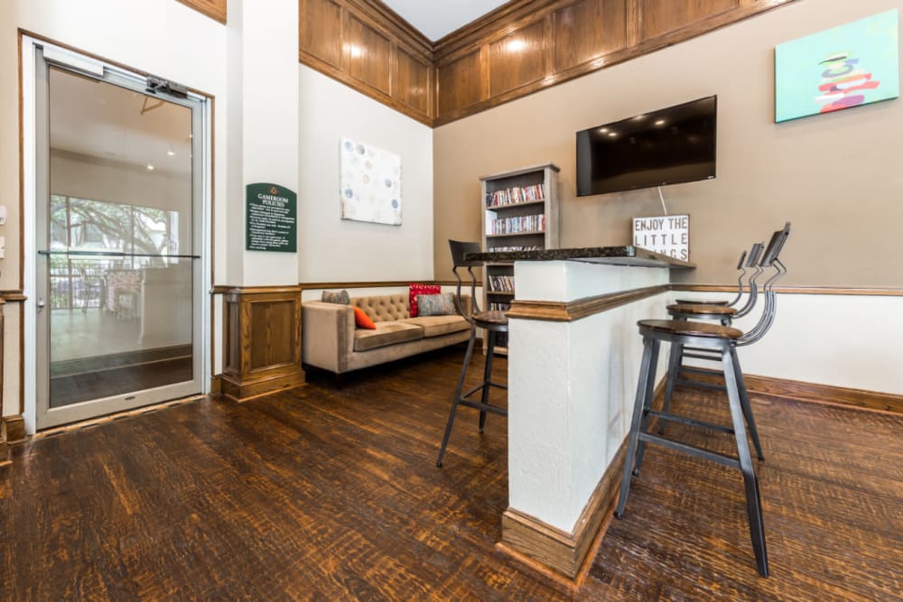 Community clubhouse game room with couch and island counter with stools at Marquis at Waterview in Richardson, Texas