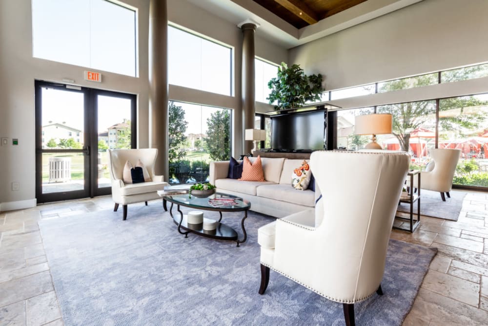 Lobby sitting area with couches, chairs, and large television monitor at Marquis at the Reserve in Katy, Texas