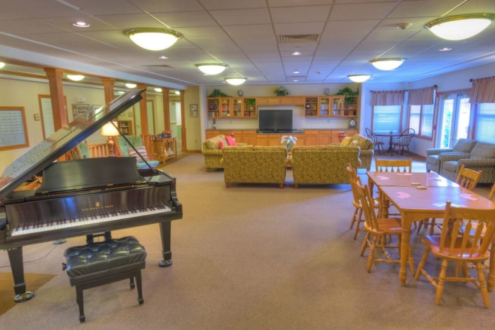 Common area with three sofas and a piano at Addington Place of Muscatine in Muscatine, Iowa