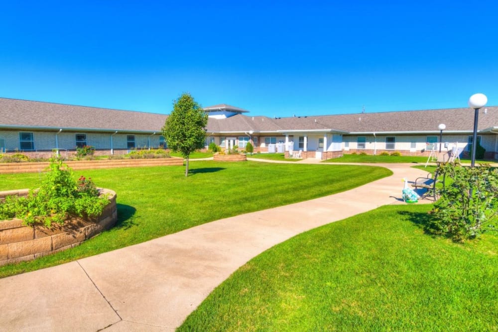 Courtyard area with green lawn and paved walkway at Addington Place of Burlington in Burlington, Iowa