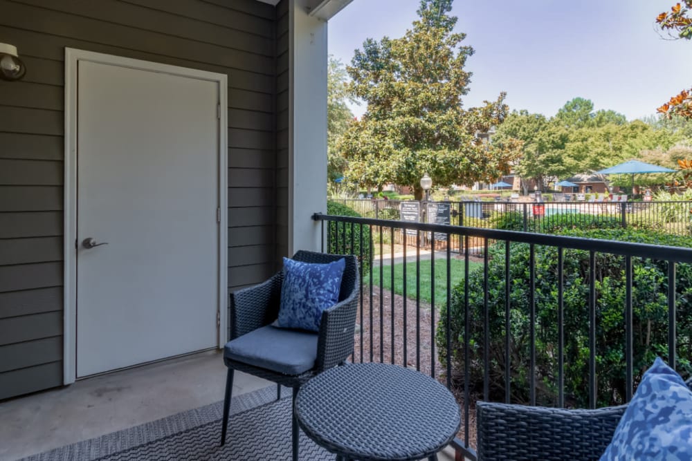 Private balcony with sitting chairs and coffee table overlooking pool area at Marquis of Carmel Valley in Charlotte, North Carolina