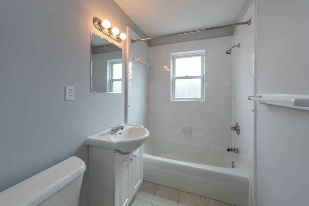 Bright bathroom with vanity light,mirror sink and bathtub at Signal Point Apartments in Mechanicsville, Virginia