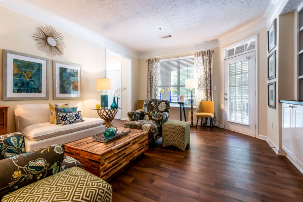 Spacious living room with wood flooring, built in shelves, and large window at Marquis at Sugarloaf in Duluth, Georgia