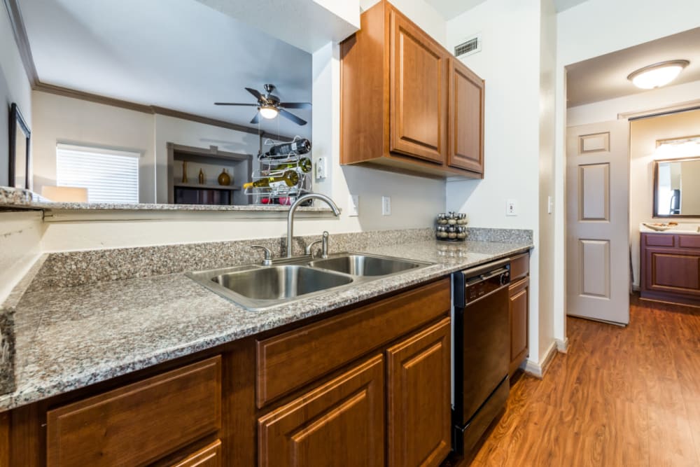 Bright kitchen area with wood cabinets and flooring at Marquis on Park Row in Houston, Texas