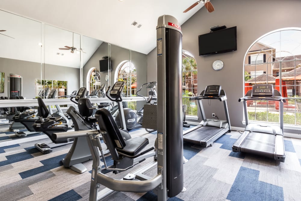 Assisted weight machines and treadmills facing pool deck at Marquis on Park Row in Houston, Texas