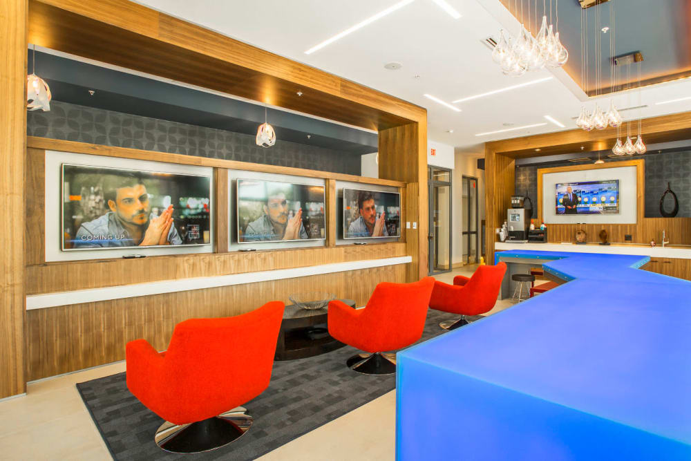 Red chairs lined in front of television screens in lobby area of Marq Midtown 205 in Charlotte, North Carolina