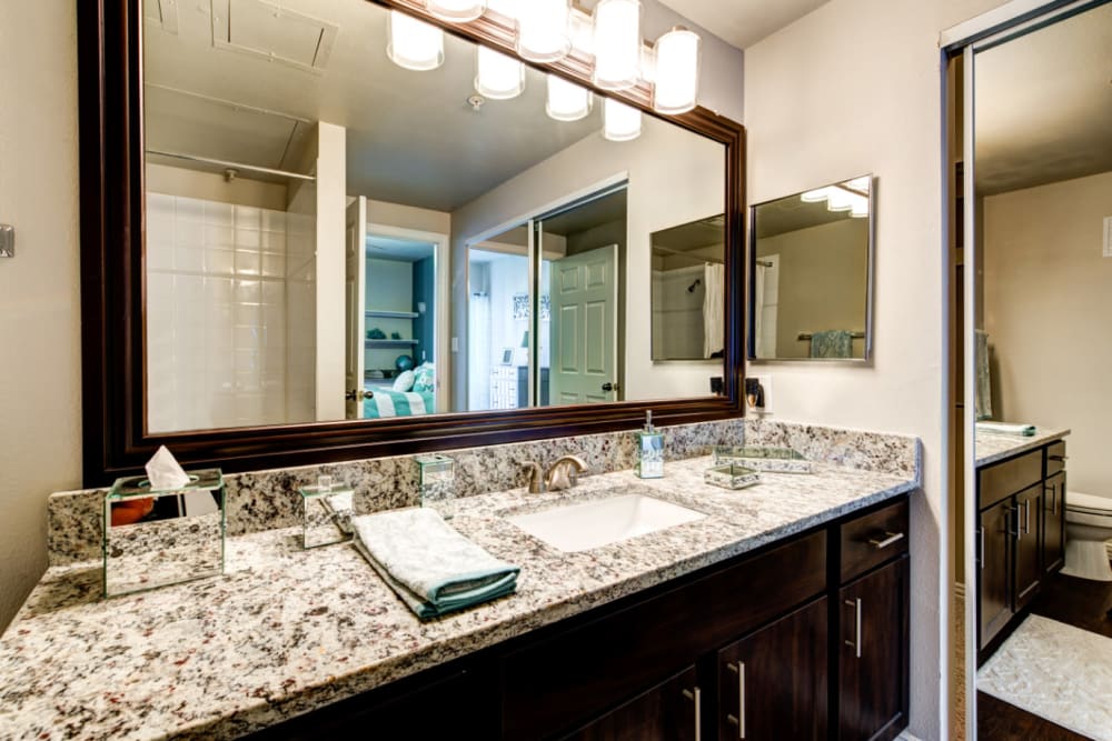 Bright bathroom with wood cabinets and granite counter at Marquis at Silver Oaks in Grapevine, Texas