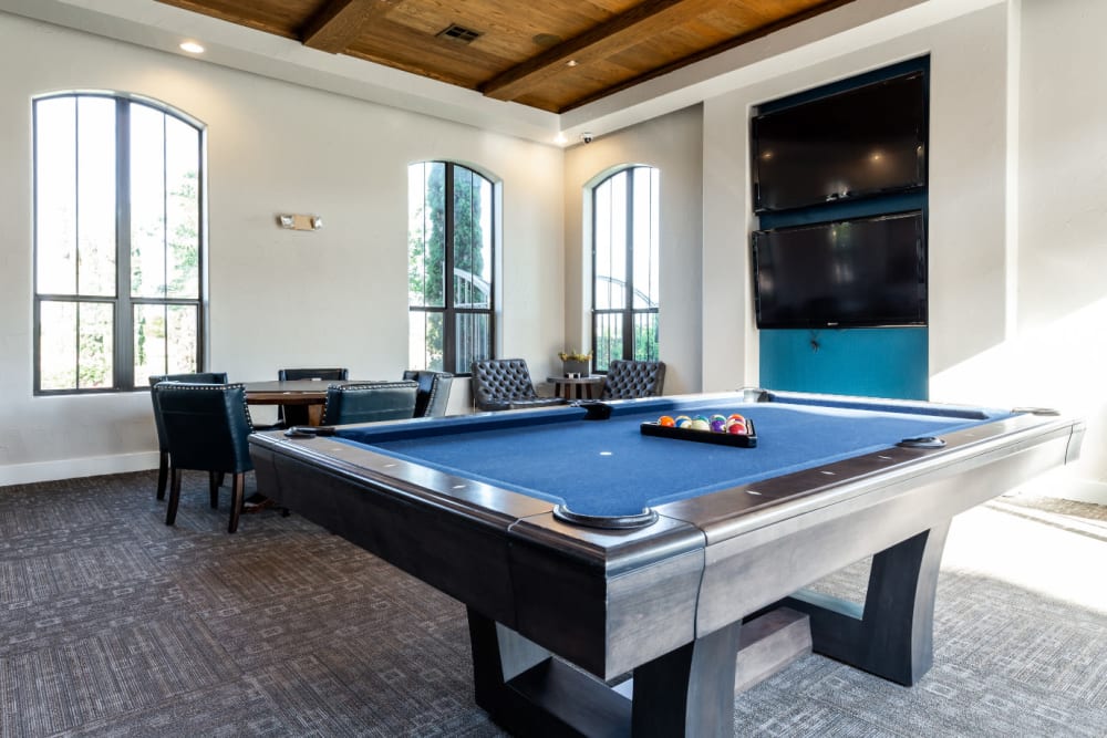 Community clubhouse game room with pool table and large monitors at Marquis at the Reserve in Katy, Texas