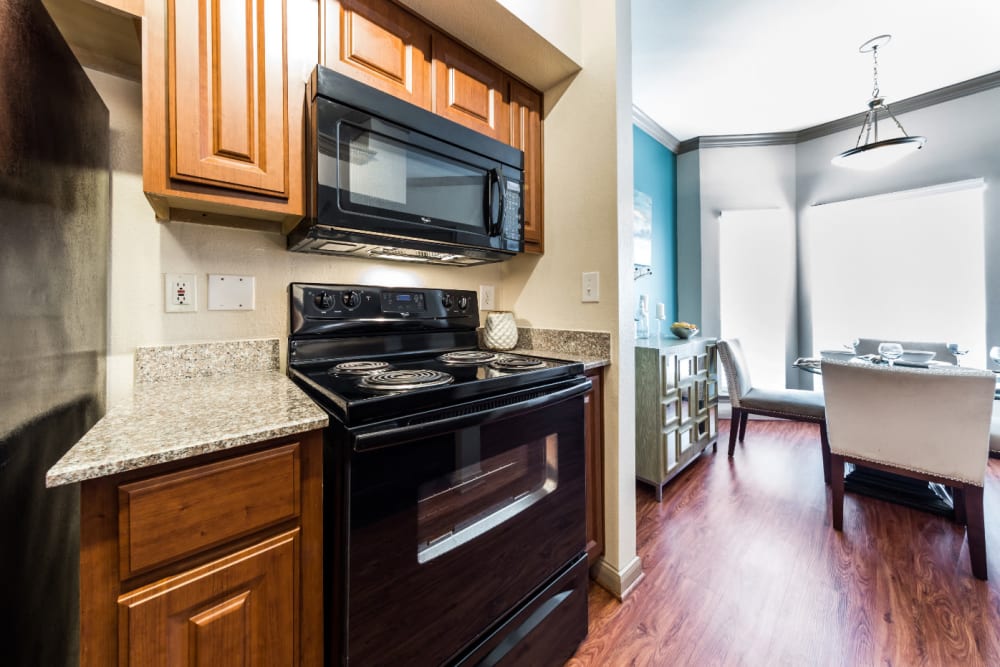 Cozy kitchen area with wood cabinets and flooring at Marquis on Park Row in Houston, Texas