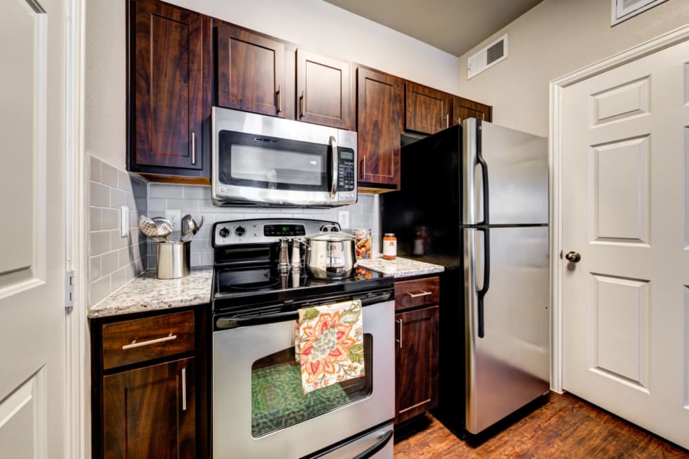 Modern style kitchen with granite counters and stainless steel appliances at Marquis at Silver Oaks in Grapevine, Texas