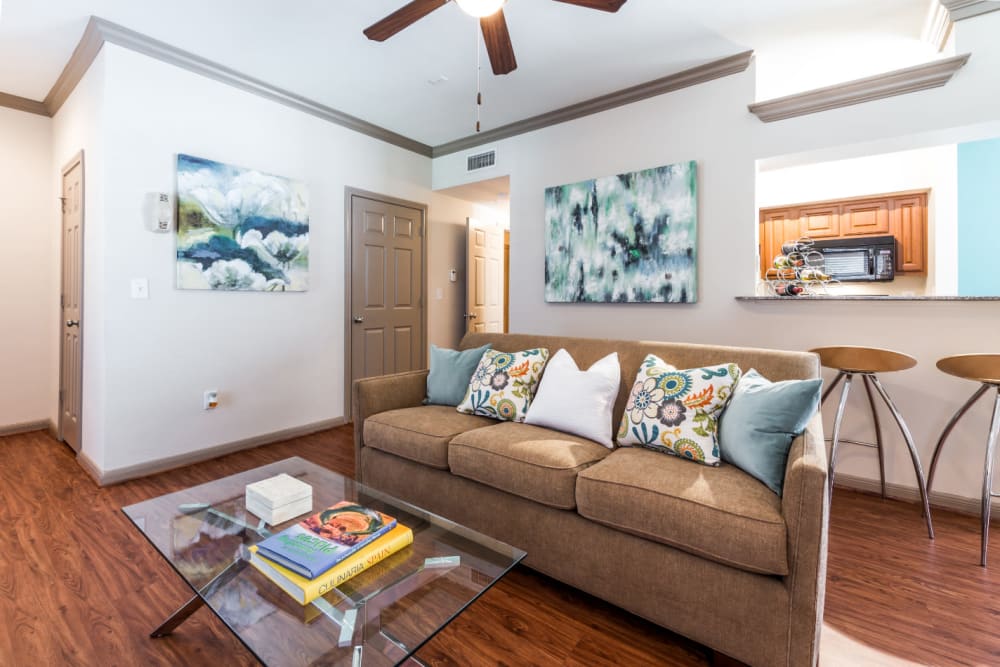Bright and cozy living room with wood flooring and ceiling fan at Marquis on Park Row in Houston, Texas