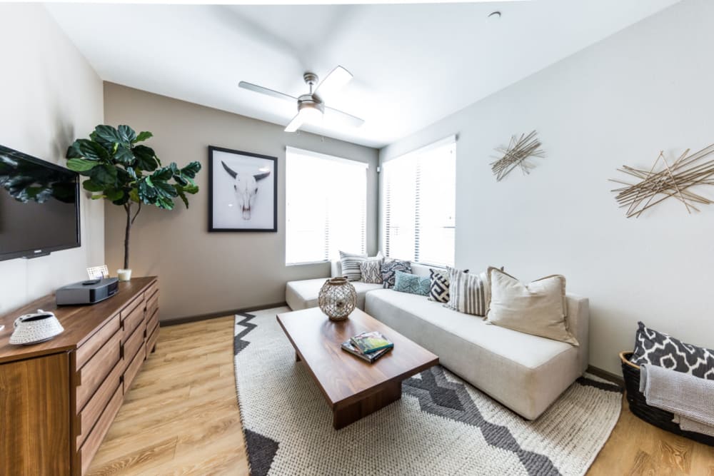 Sleek style living room with large windows and wood flooring at Marquis at Desert Ridge in Phoenix, Arizona