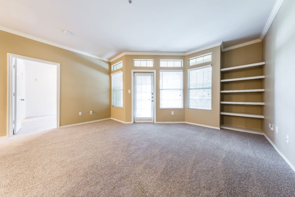 Bright and open carpeted living area with built-in shelves at Marquis at Barton Trails in Austin, Texas
