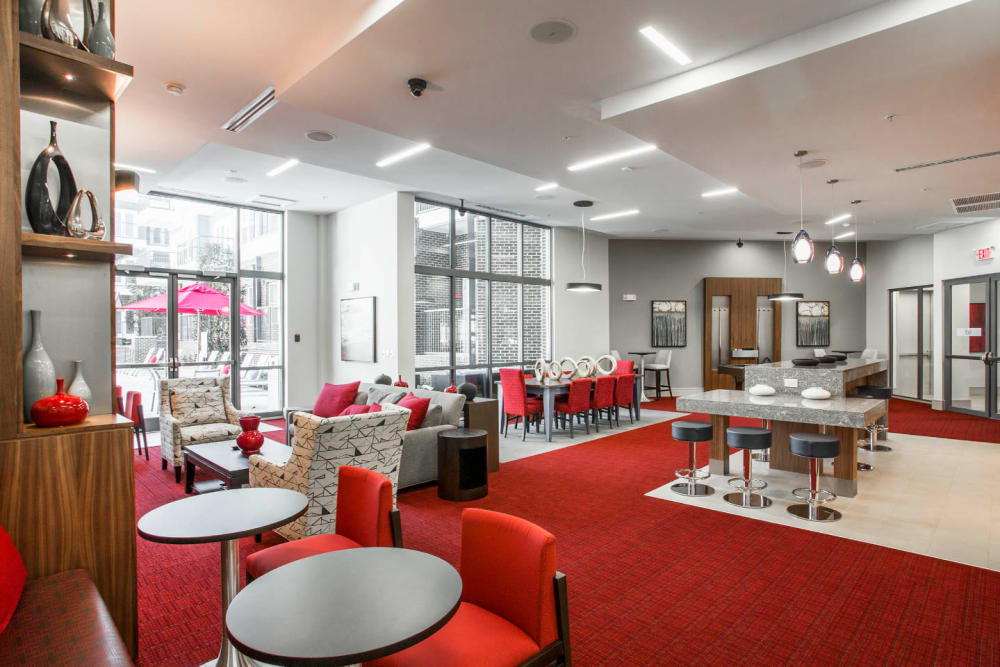 Large colorful community room with dining, kitchen, pool, and sitting areas at Marq Midtown 205 in Charlotte, North Carolina