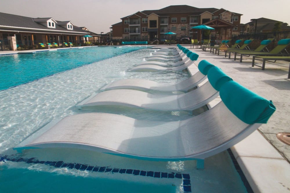 Row of lounge chairs at the sparking pool of Biltmore at the Park in Pflugerville, Texas